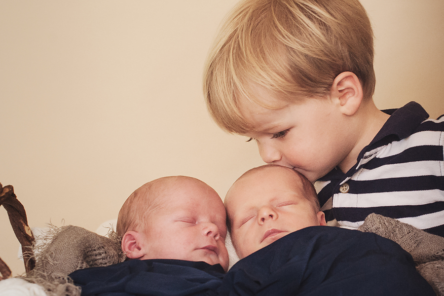 twin babies sleeping and toddler brother is kissing them