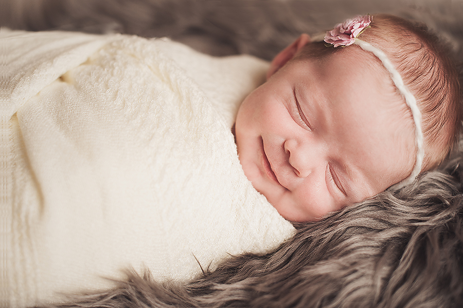 sleeping baby smiling wrapped in a white blanket