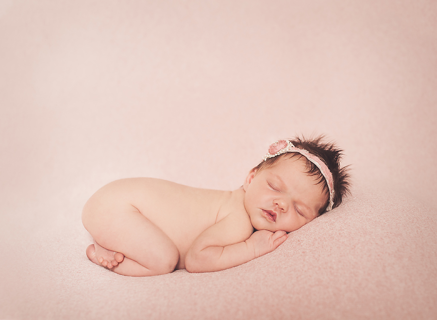 sleeping baby on pink blanket wearing headband