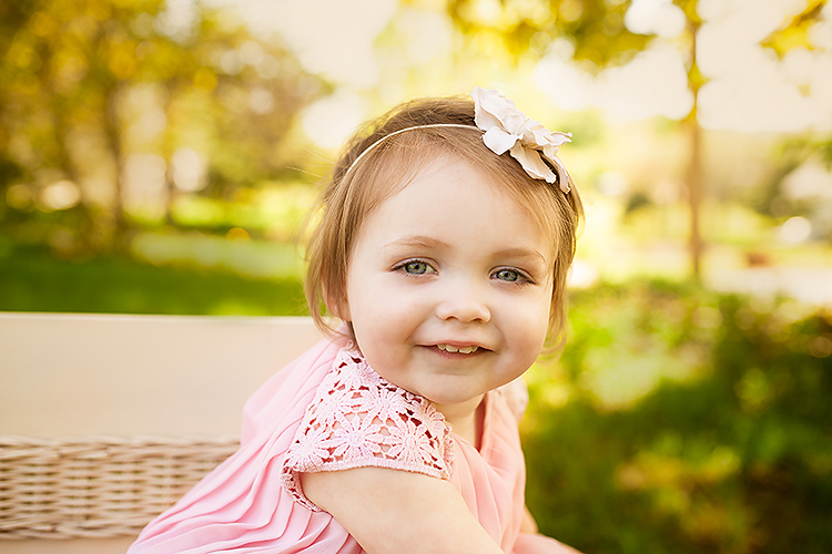 Little girl smiling at the camera in a pink dress