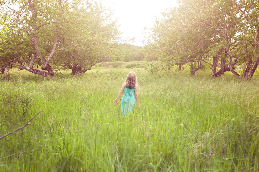 little girl wandering through a field in a turquoise dress