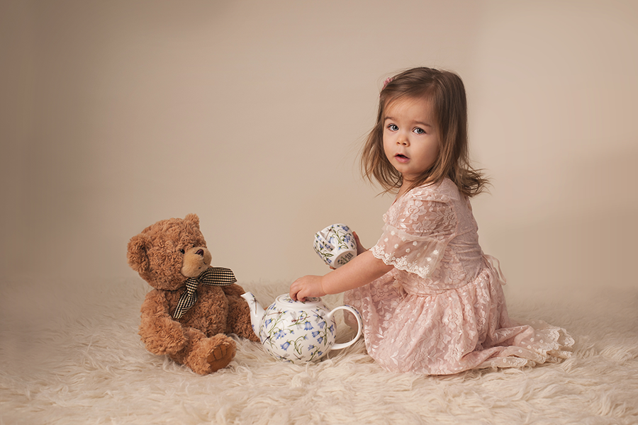 little girl having a tea party with her teddy bear