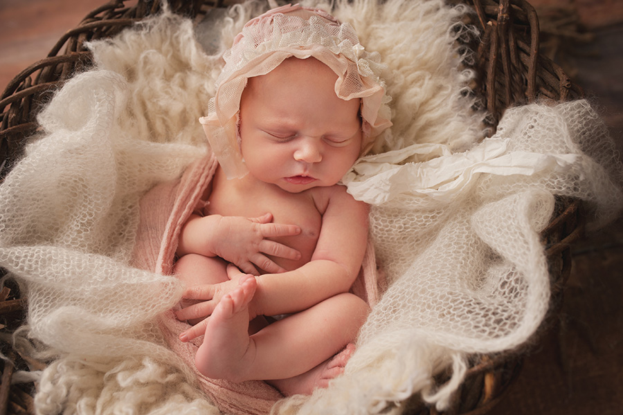 newborn girl in frilly pink bonnet