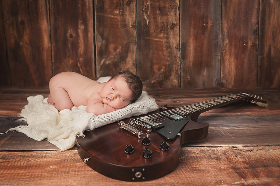 baby girl laying on a guitar 