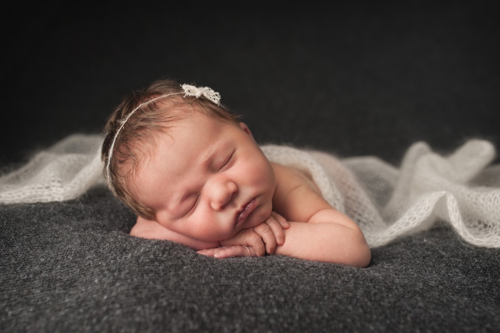 baby girl on grey with white blanket 