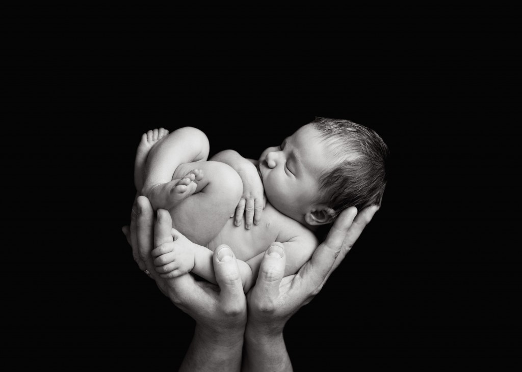 black and white image of baby being held up in the air