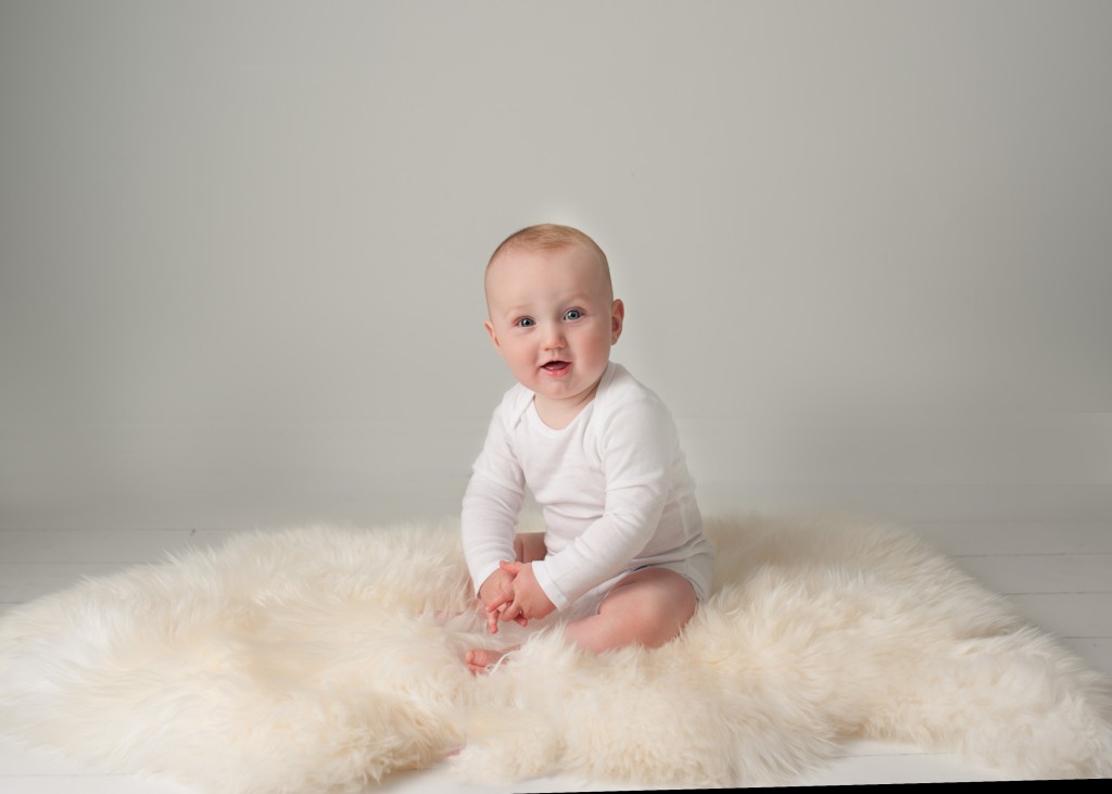 baby wearing a white shirt sitting on a white rug
