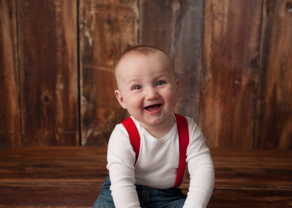 baby with red suspenders laughing 