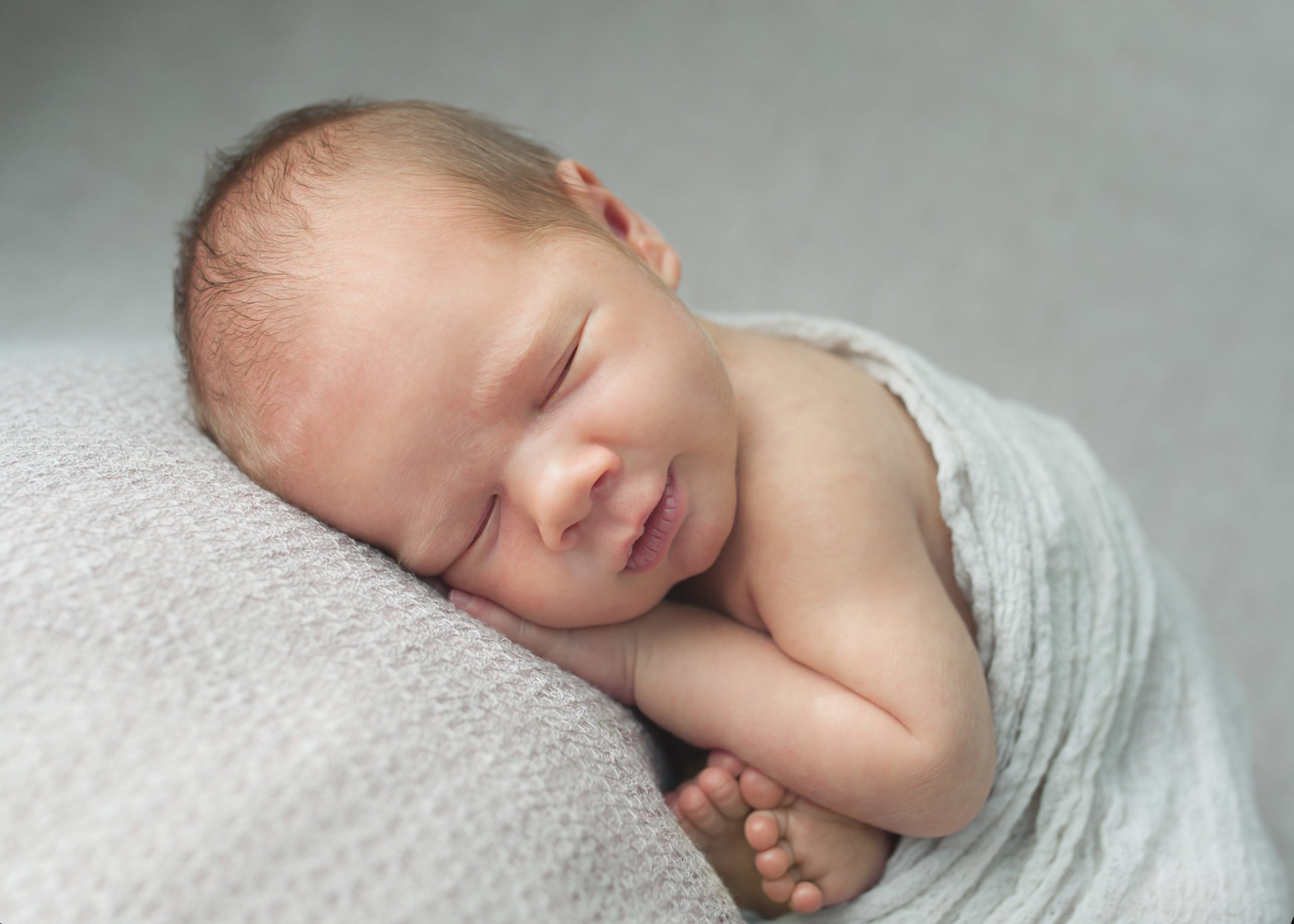 brand new baby boy curled up smiling