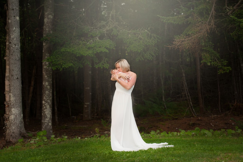 Saint John photographer new mom holding her new baby  in white gown