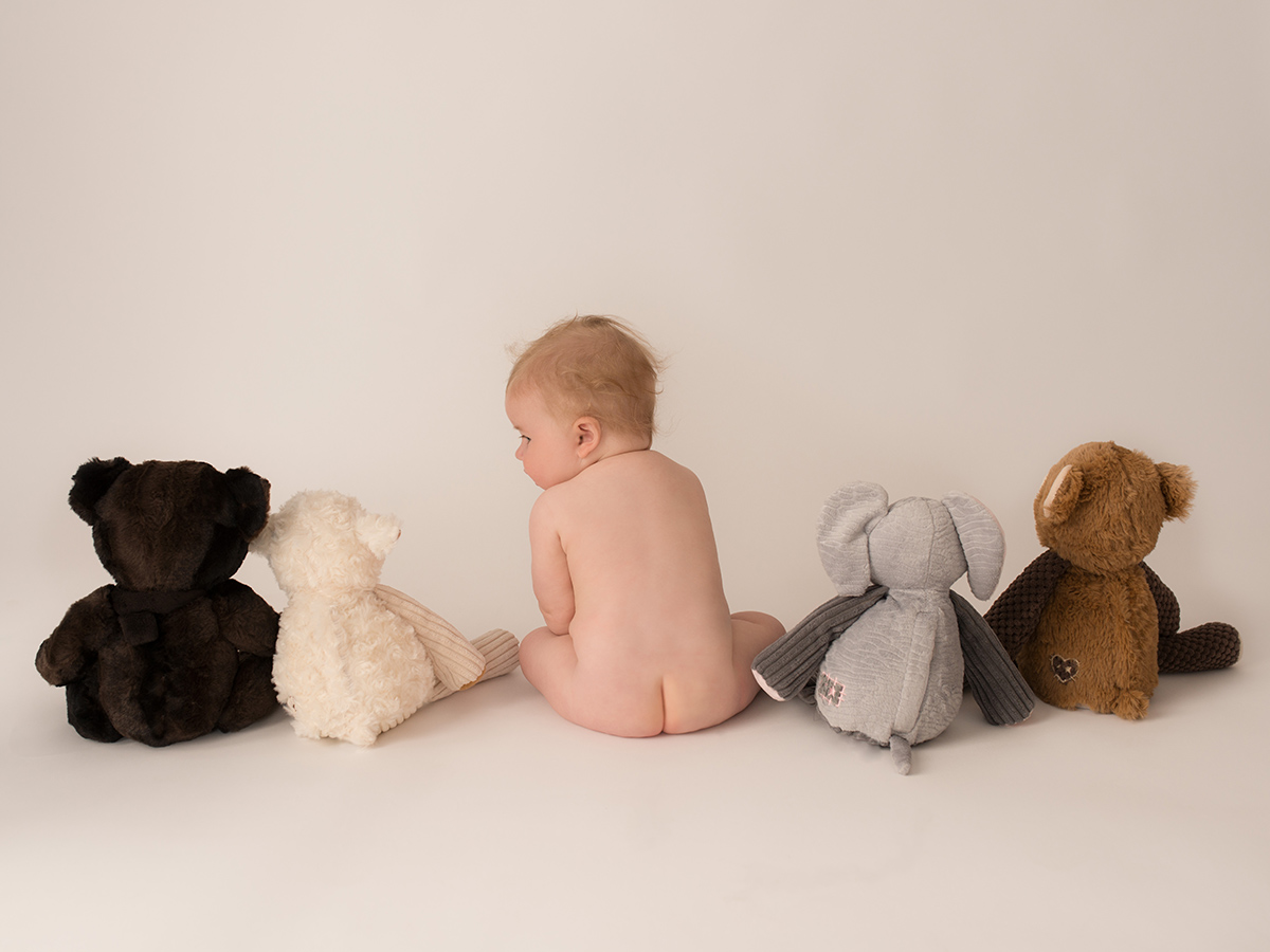 Naked baby sitting with bum showing and stuffed animals surrounding him | Saint John Baby Photographer