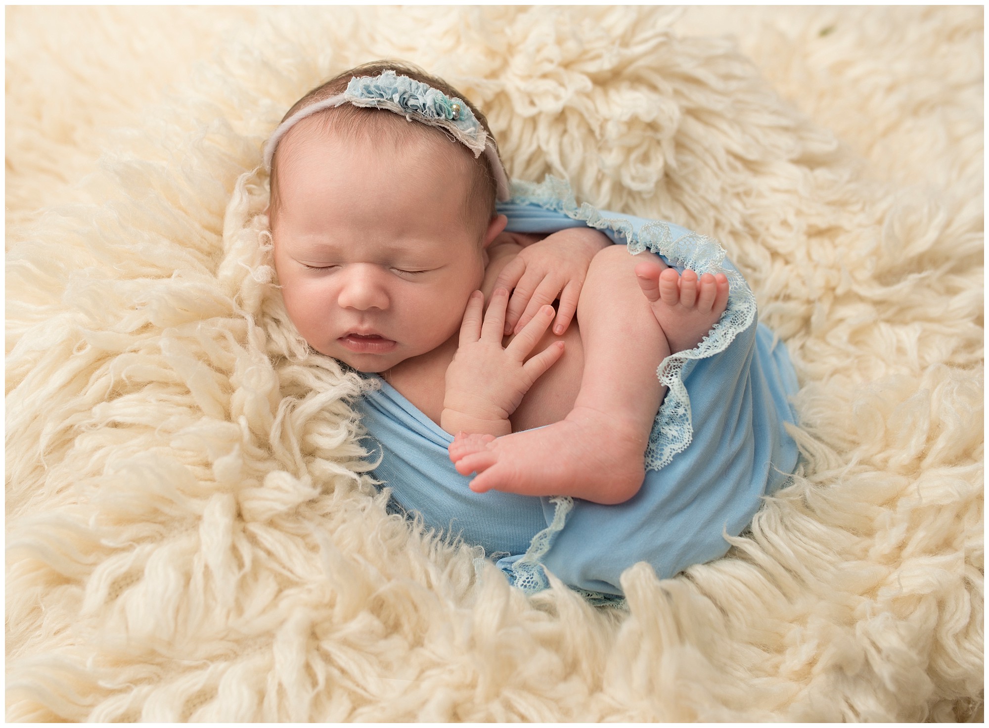 sleeping newborn baby girl wrapped in blue fabric