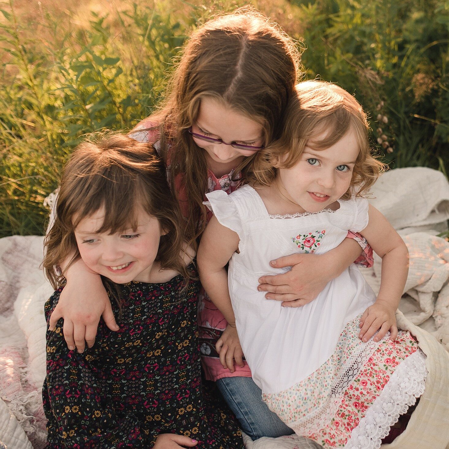 Three little girls sitting on the grass during a family session in Saint John, NB