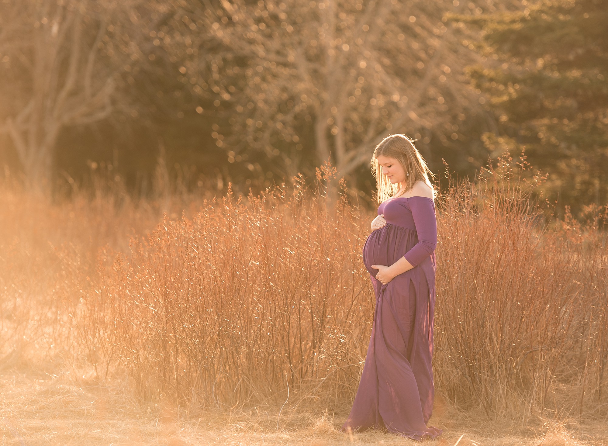 a pregnant mom in the grass wearing a purple gown