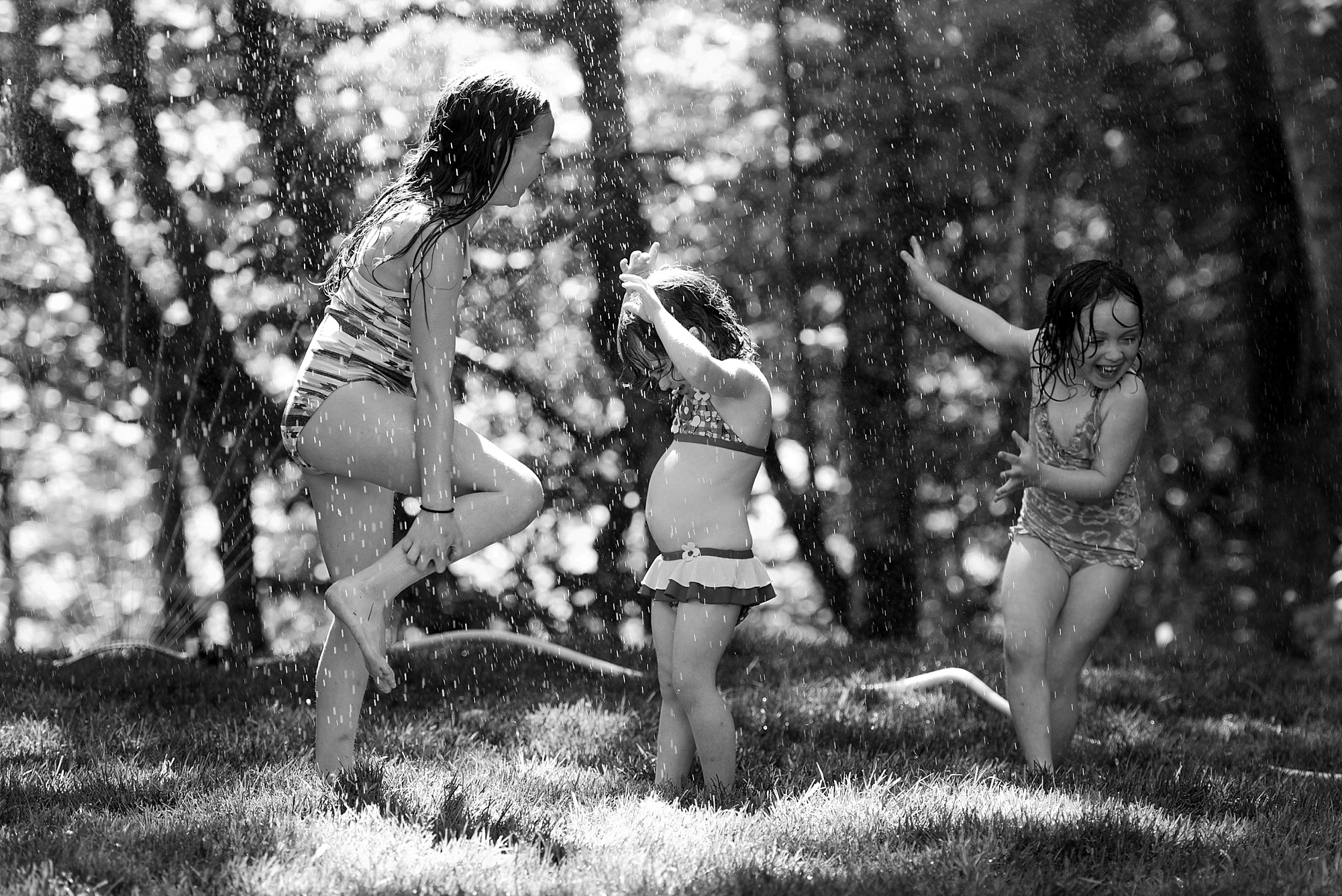 little girls running through the sprinkler black and white