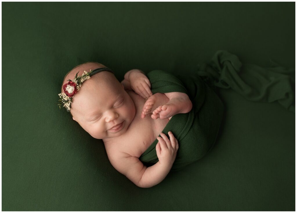 a picture of a baby who was born premature and having her newborn pictures taken. She is smiling on a green blanket