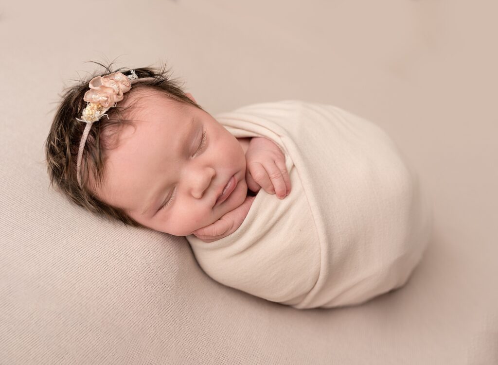 the best newborn picture in Saint John of a little girl wrapped in soft pink scarf with a floral headband