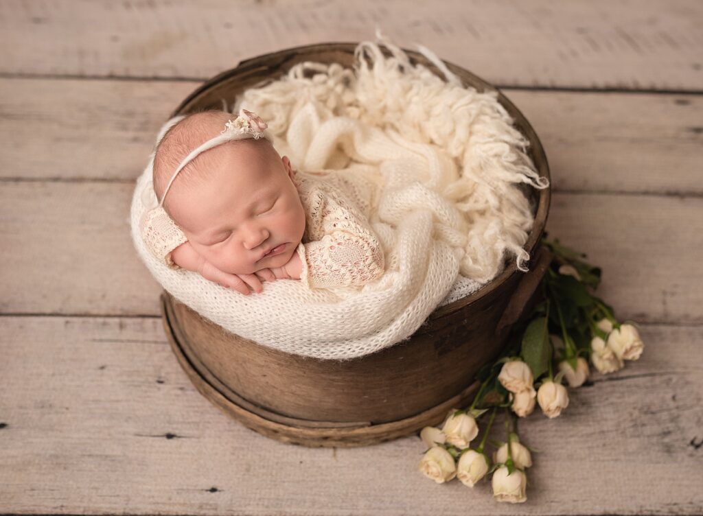 baby girl wear a lacy outfit sleeping in a vintage prop with roses