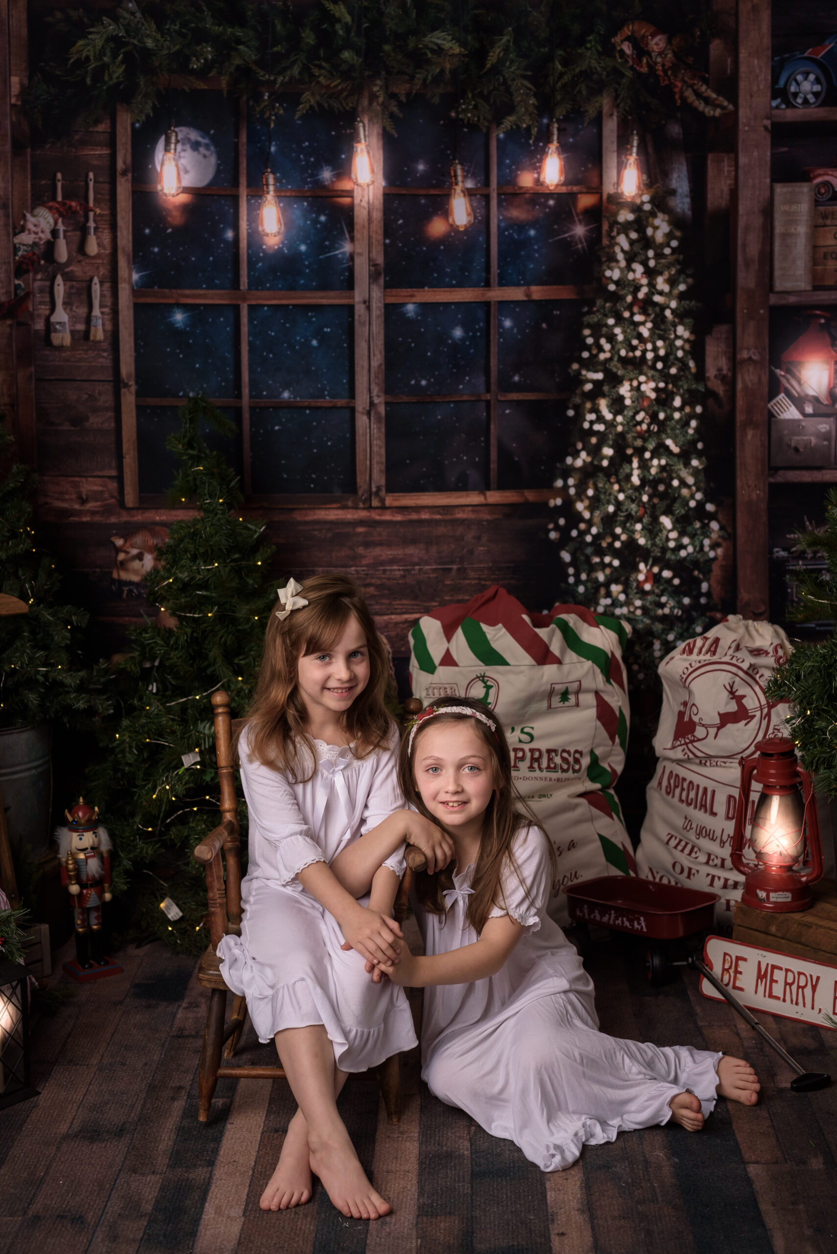 two little girls in white vintage nighties in a magical room decorated for Christmas and posing for their Christmas mini session in Saint John, NB
