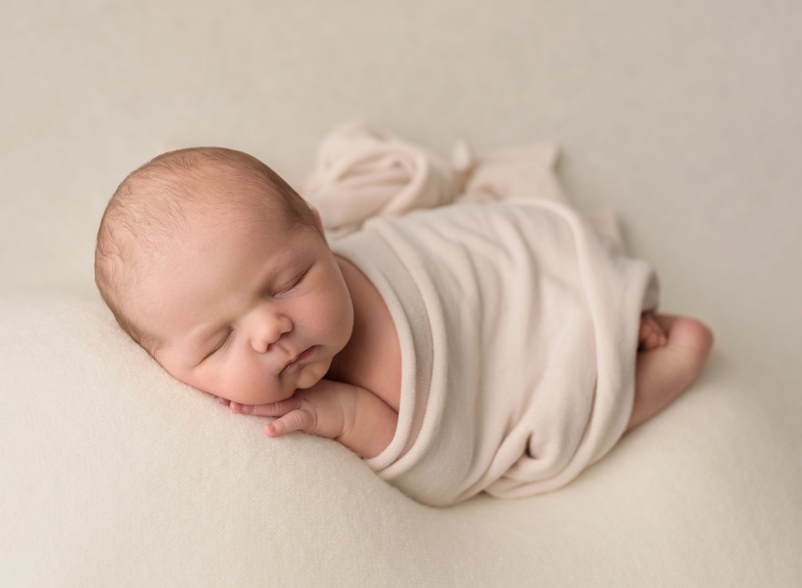 baby wrapped in a cream blanket in a saint john photography studio