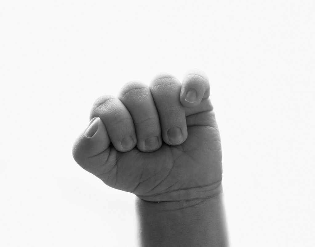 black and white picture of a clenched hand from relaxed newborn posing