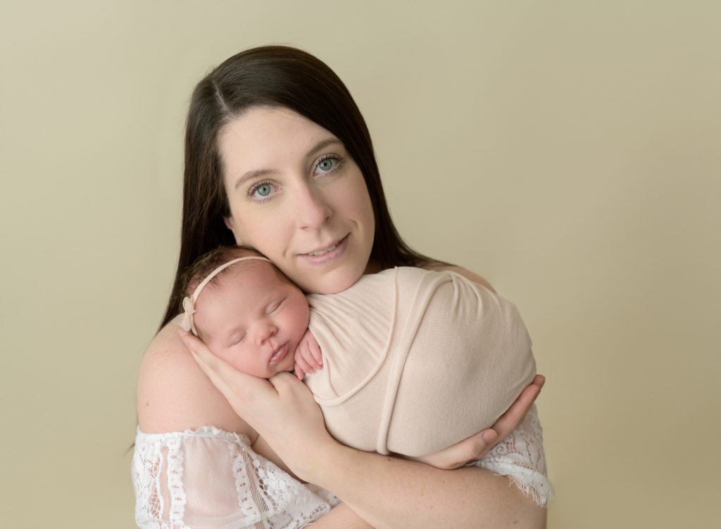 A woman is holding her new baby girl at a photography studio.