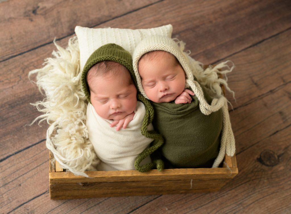 This is an example of how twin sessions are a little different because the twins sleeping in the little box are not wearing matching outfits but rather coordinating .